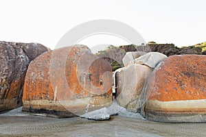 A boy standing between two boulders at the beach