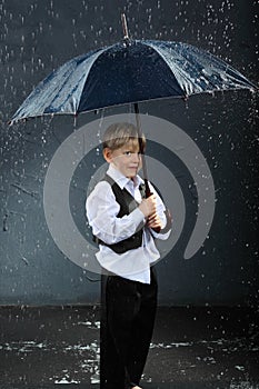 Boy standing under umbrella in rain