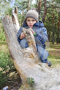 Boy standing in the woods on a log.