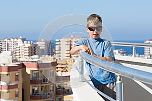A boy stands on balcony of hotel