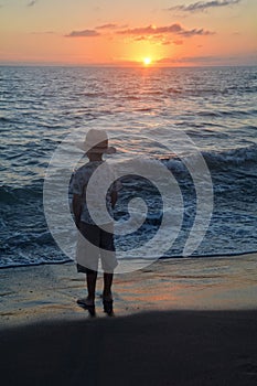 Boy stands on the beach at the sundown