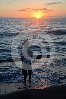 Boy stands on the beach at the sundown