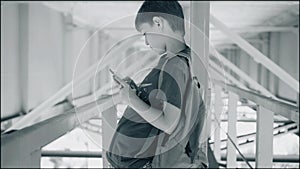 The boy stands in a cool metal corridor. Atmospheric shots. The boy looks at the smartphone. It`s under the bridge.