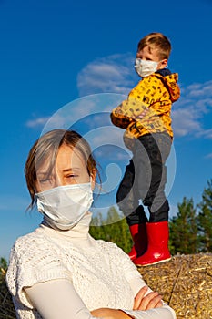 Boy stands on a haystack against a blue sky, his mother stands in front of him