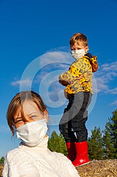 Boy stands on a haystack against a blue sky, his mother stands in front of him