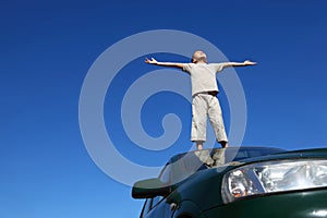 Boy stands on head of car widely placing hands photo