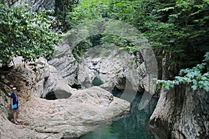 Boy stands near beautiful mountain river at summer photo