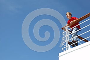 Boy stands at railing on deck of ship