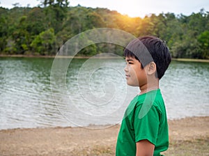 A boy stands by the reservoir in the evening. It shows looking at the goals in life