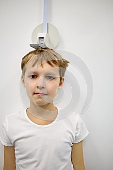 Boy stands at stadiometer near photo