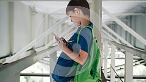 The boy stands under the bridge. Nice light from the water. Metal technical constructions.