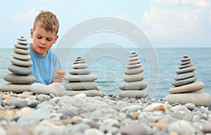 Boy and stone stacks on pebble beach