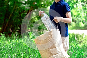 The boy on the street collects plastic in a bag.