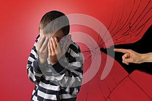 Boy in a striped sweater, accusing the gesture of an adult`s hand, cringed and covered his face with fear, background with cracks