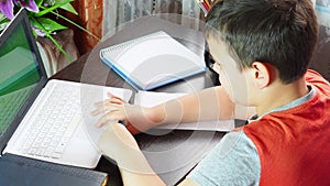 boy studies at home at the computer. remote education, school child learns lessons online using video broadcasting and