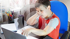 boy studies at home at the computer. remote education, school child learns lessons online using video broadcasting and