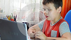 boy studies at home at the computer. remote education, school child learns lessons online using video broadcasting and