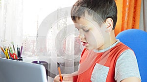 boy studies at home at the computer. remote education, school child learns lessons online using video broadcasting and