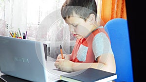 boy studies at home at the computer. remote education, school child learns lessons online using video broadcasting and