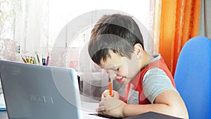 boy studies at home at the computer. remote education, school child learns lessons online using video broadcasting and