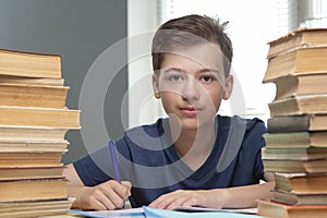 Boy studing at table on blue background and many book