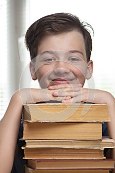 Boy studing at table on blue background and many book