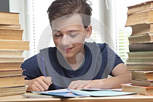 Boy studing at table on blue background and many book