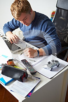 Boy Studying In Bedroom Using Laptop