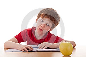 Boy studying and distracted with an apple