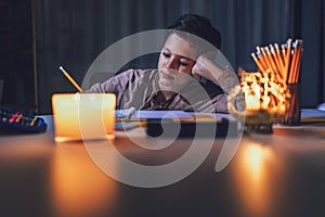 Boy studying in low light with a burning candle.  Power outage, energy crisis concept