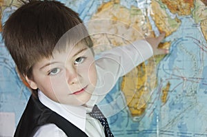 The boy is studying the map of the world