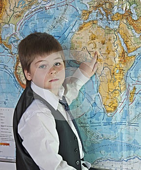 The boy is studying map of the world