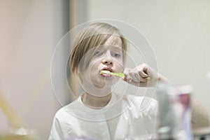 A boy with a stylish haircut brushes his teeth