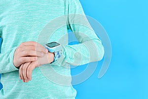 Boy with stylish smart watch on light blue background, closeup