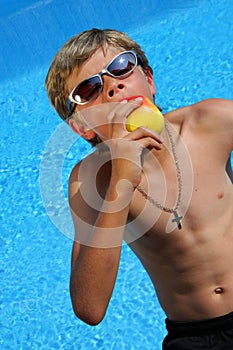 Boy with sun glasses eating an apple