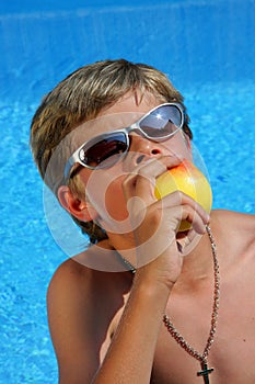 Boy with sun glasses eating an apple with pleasure