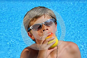 Boy with sun glasses eating a delicious apple