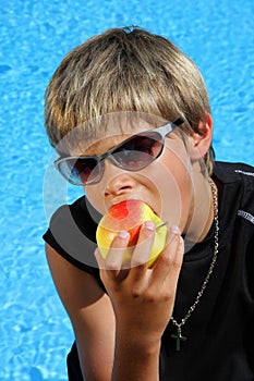 Boy with sun glasses and t-shirt eating an apple