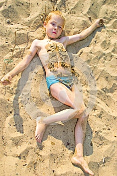 Boy sunbathes on the sand