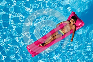 Boy sunbathing on inflatable lounge in the pool