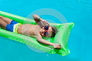 Boy with sunglasses relaxing in swimming pool