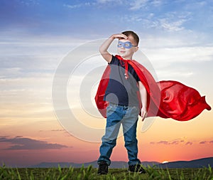 A boy in a Superman costume stands