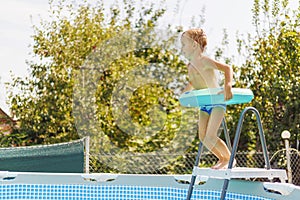 Boy with Surfboard Float by Above-Ground Pool