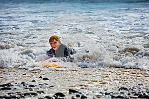 Boy with surfboard get to shore after surfing smiling