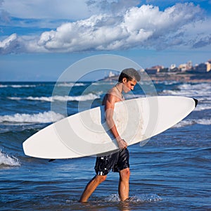 Boy surfer holding surfboard caming out from the waves