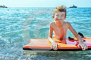 Boy surfing on tropical beach. Family summer vacation. Kid on surf body board. Travel with children. Water and beach