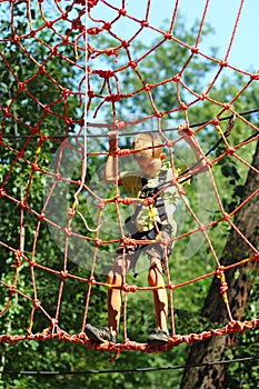 Boy surmounting obstacle course in the rope park photo