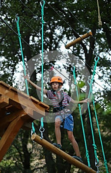 Boy surmounting obstacle course in the outdoor rope park photo