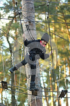 Boy surmounting obstacle course in the outdoor rope park photo