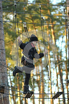 Boy surmounting obstacle course in the outdoor rope park photo